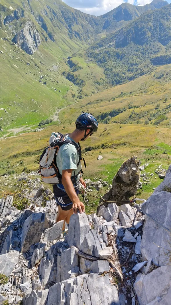 Andrea Murisasco scende una cresta rocciosa sopra una valle verde