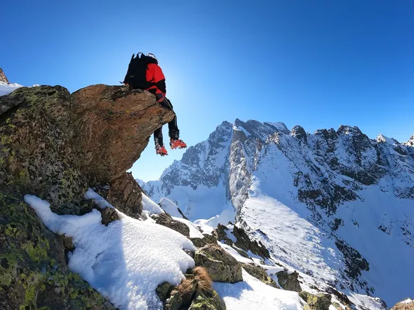 Andrea Murisasco seduto su uno sperone di roccia sopra le cime innevate