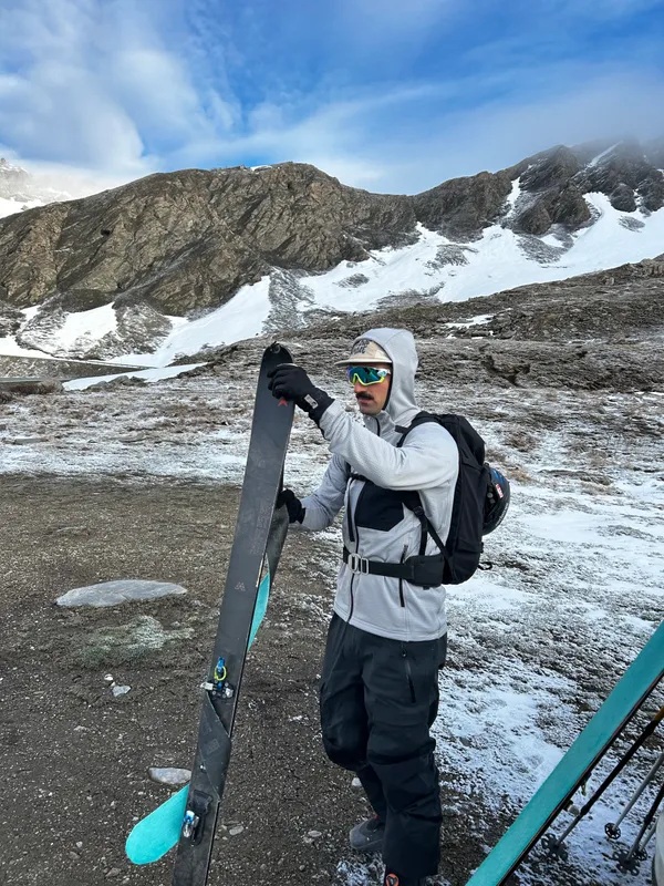 Andrea Murisasco con gli sci in mano ai piedi di un ghiacciaio